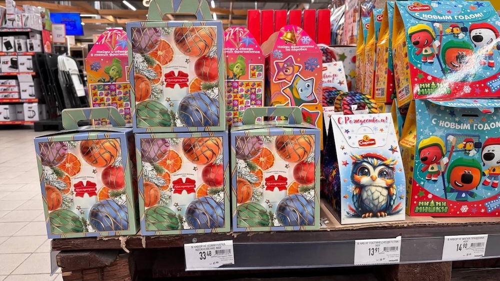 Новогодние сладкие подарки на полках в магазине.